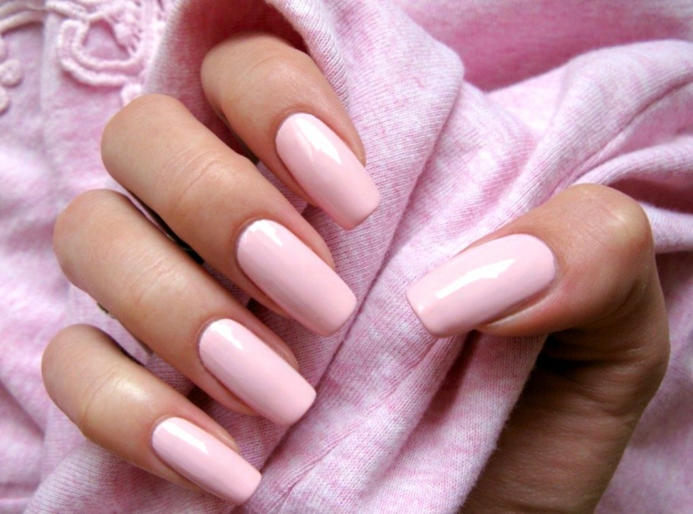 La mano di una donna, unghie forma squadrata, nail art rosa cipria 