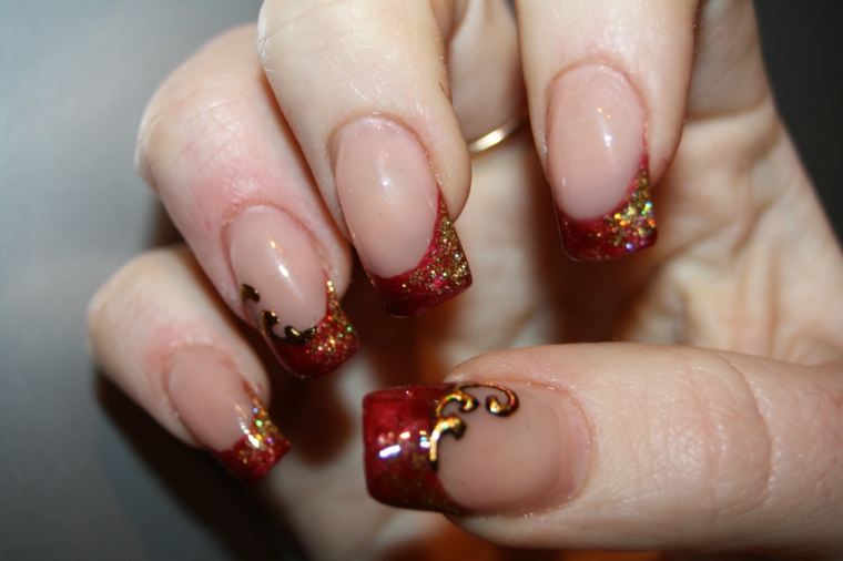 Unghie con french manicure particolare di colore rosso e glitter glossy in oro 