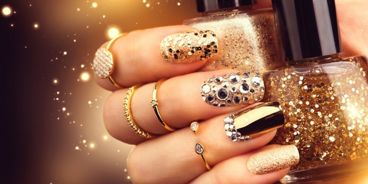 Decorazioni unghie lunghe con brillantini, glitter e smalto mat, tanti anelli in oro 